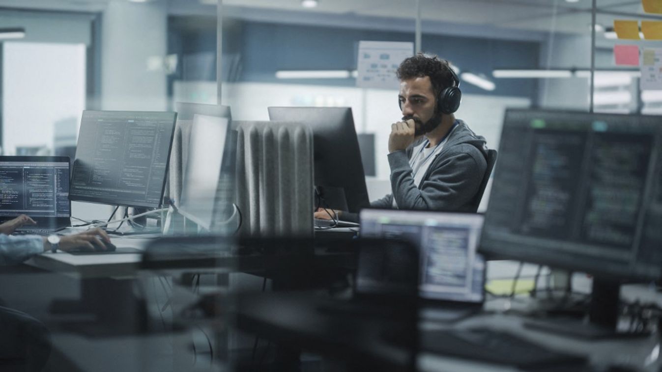 Software engineer wearing headphones working on computer