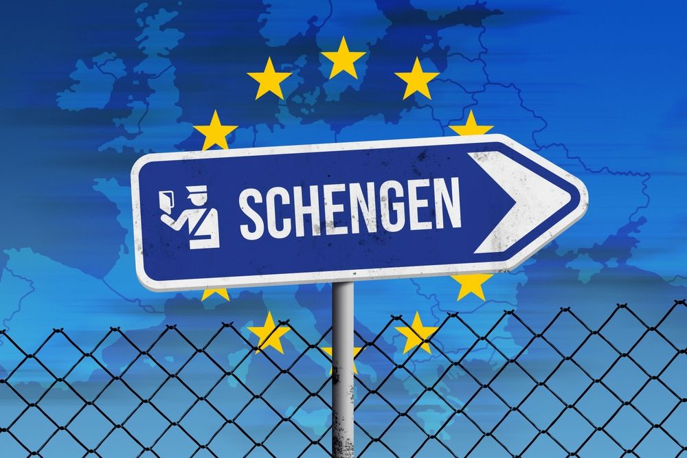 Schengen,Sign,And,Europe,Map,Against,Blue,Sky,And,Fence