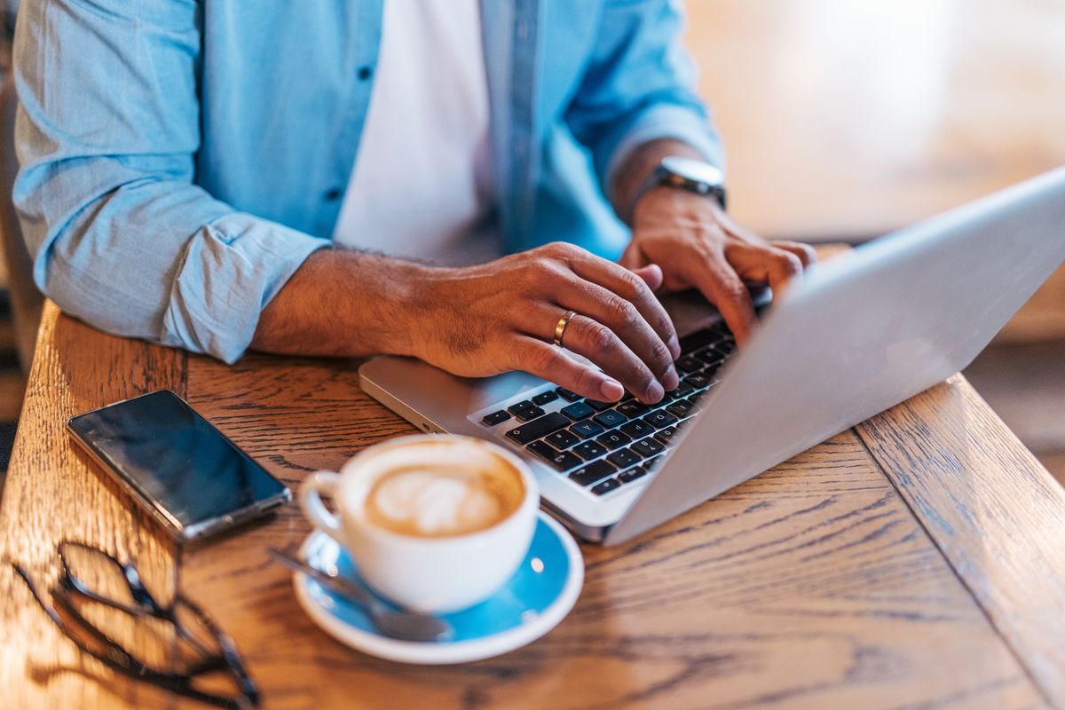 Happy handsome mid adult  man enjoying a Peaceful Coffee Break in a Café and using laptop