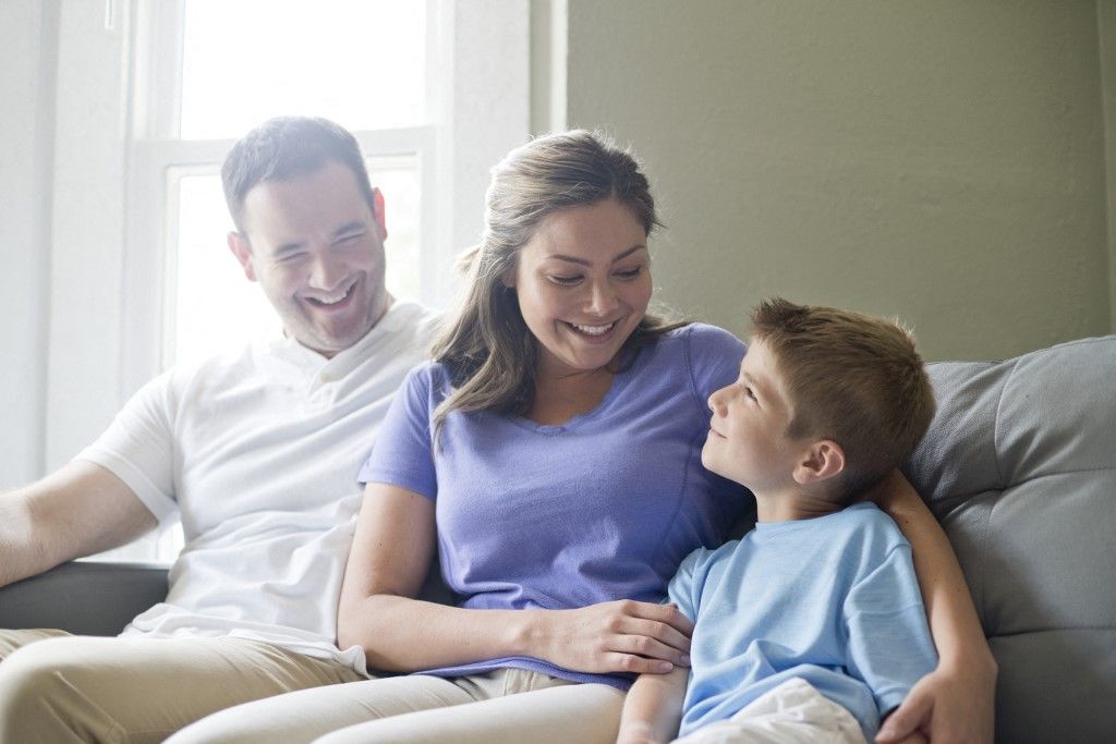 Boy sitting on sofa with his mother and father, portrait gazdaság család
