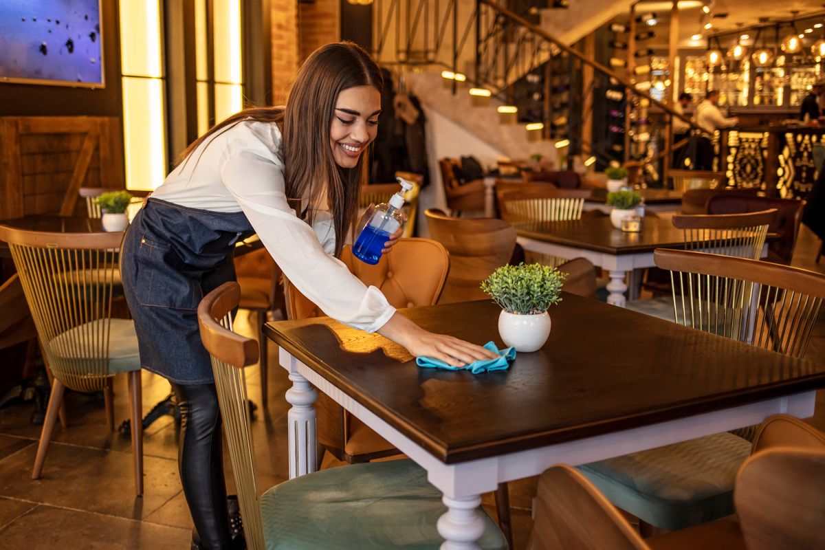 Waitress cleaning a table at a restaurant.