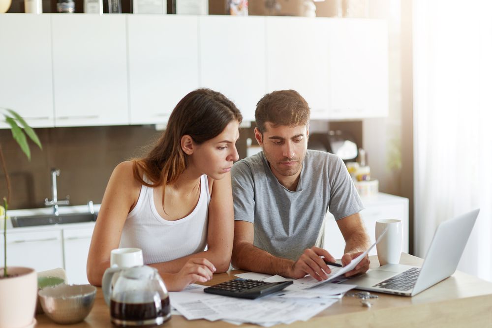 Portrait,Of,Serious,Man,And,Female,Sitting,At,Kitchen,Table,