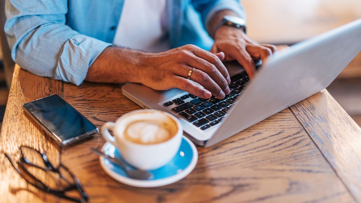 Happy handsome mid adult  man enjoying a Peaceful Coffee Break in a Café and using laptop