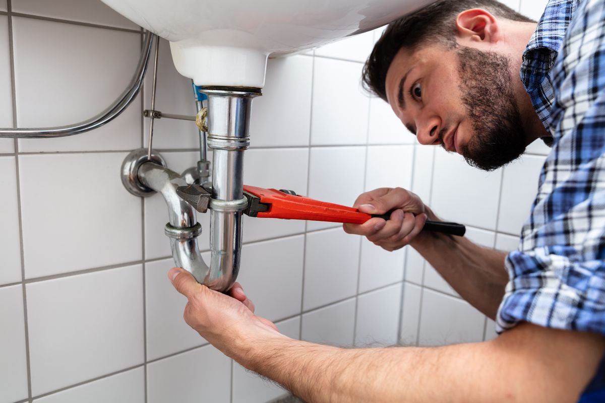 Plumber Repairing Sink In Bathroom