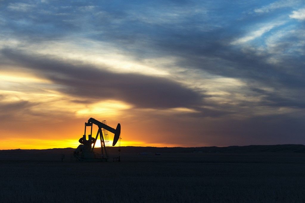 A pumpjack at an oil drilling site at sunset.