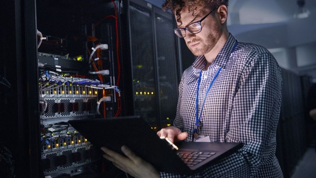 Focused IT technician working at laptop