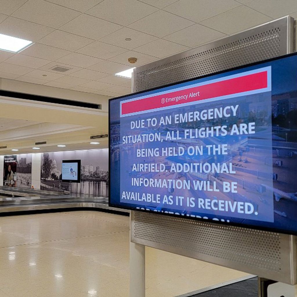 An information screen in Reagan National Airport's empty baggage claim area displays emergency instructions after a plane crashed into the Potomac River outside Washington, DC, January 29, 2025. A regional jet from Kansas crashed into Washington's Potomac River after colliding mid-air with a military helicopter near Reagan National Airport, officials said January 29, prompting a major emergency response and grounding all flights. (Photo by Ulysse BELLIER / AFP)