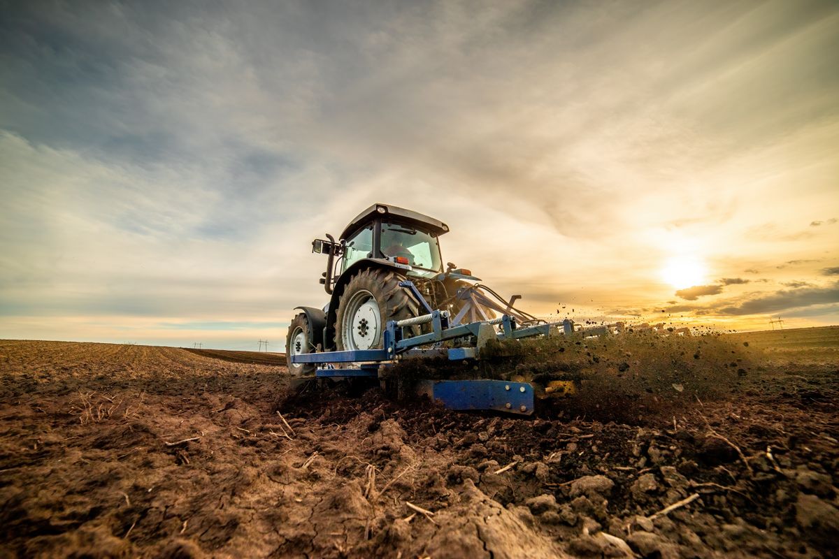 Wide-angle,View,Of,A,Tractor,Plowing,Farmland,Against,A,Dramatic