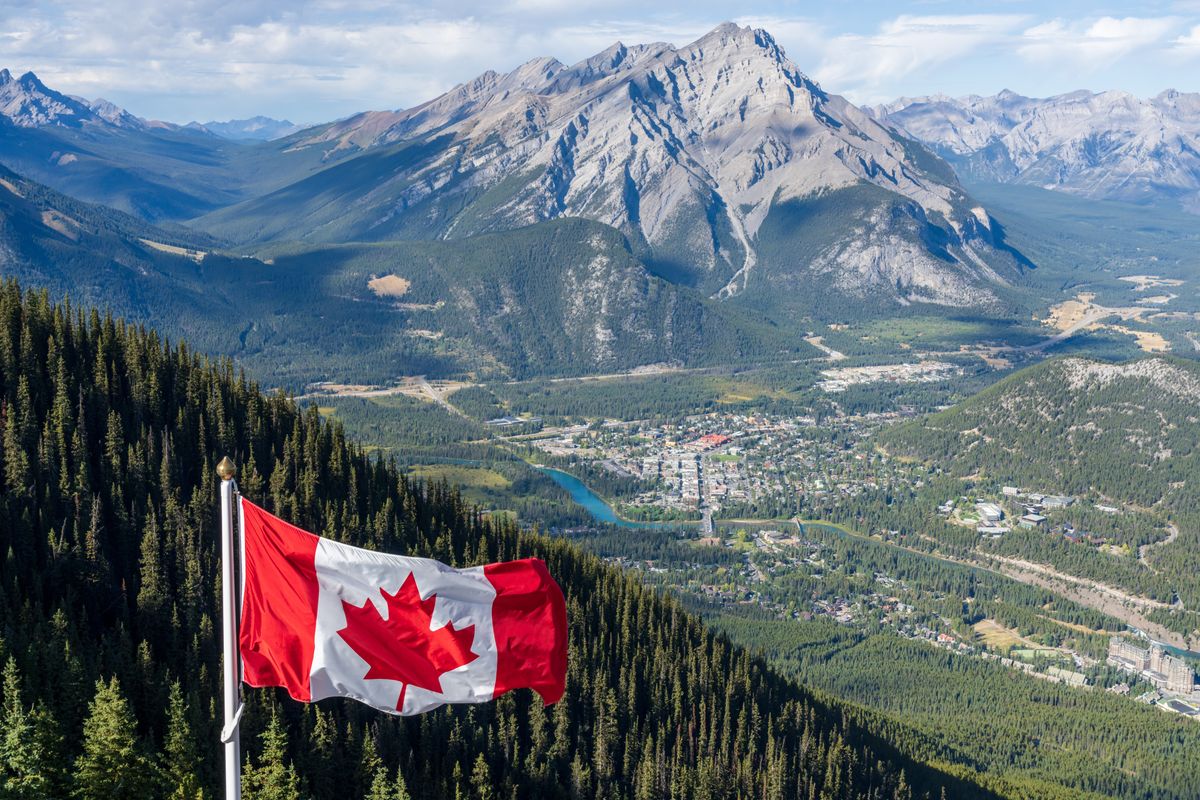 National,Flag,Of,Canada,With,Town,Of,Banff,In,Background.