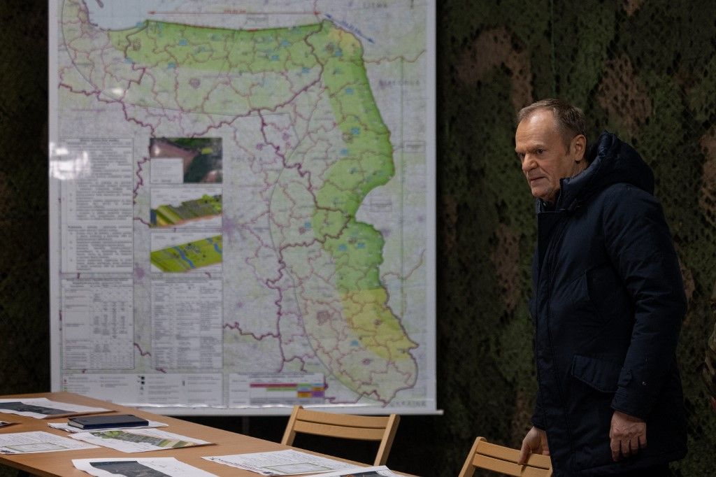 Donald Tusk lengyel miniszterelnök egy térkép mellett áll a lengyel-orosz határon, a „Keleti Pajzs” erődítmény első elkészült szakaszának vizsgálata előtt 2024. november 30-án