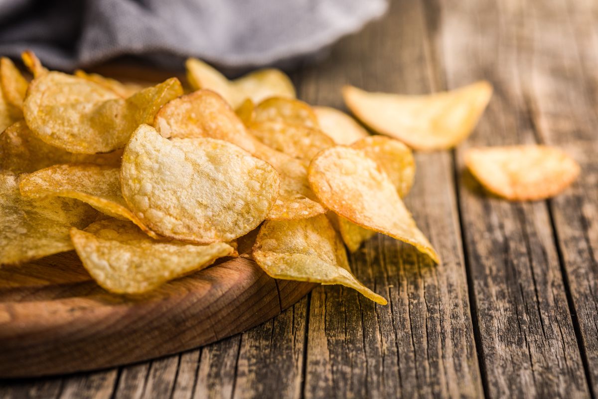 Crispy,Potato,Chips,On,Cutting,Board,On,A,Wooden,Table, burgonya, chipsz, chips, krumpli csipsz chips, müller