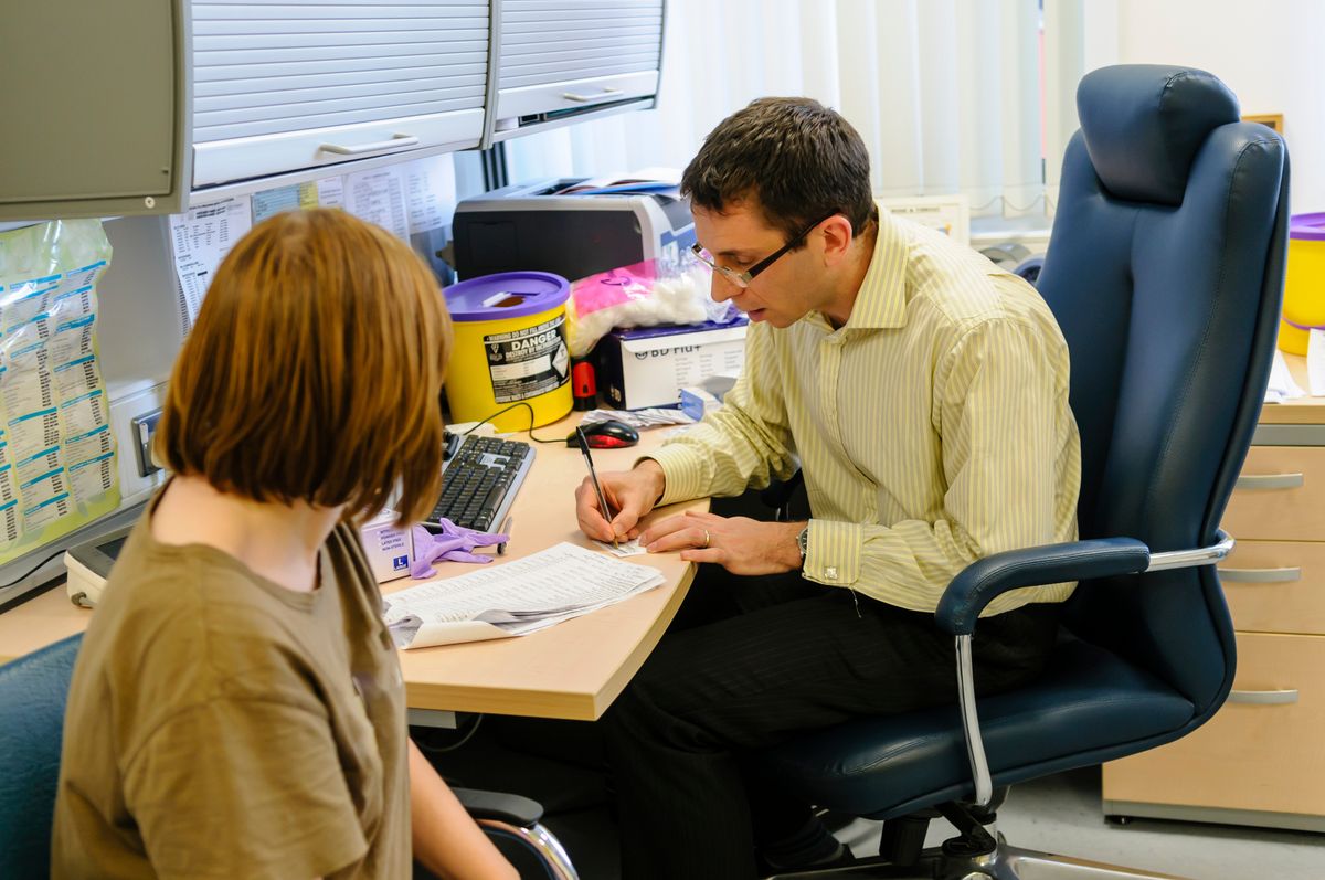brit egészségügy Doctor,And,Patient,In,A,Consulting,Room,At,A,Gp