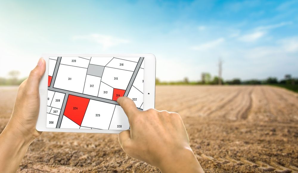 Man,Holding,A,Tablet,Looking,At,Lots,Of,Lands.,Land