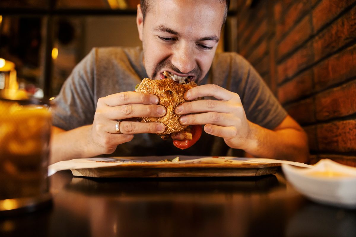Close,Up,Of,A,Starving,Man,Eating,Hamburger,In,A