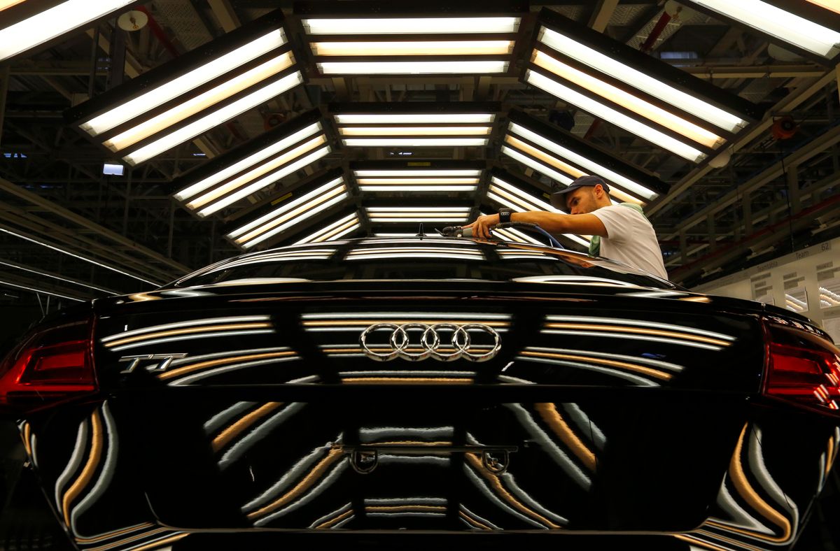 A worker stands next to a car on the assembly line as serial production of the new Audi TT roadster starts at the Audi plant in Gyor