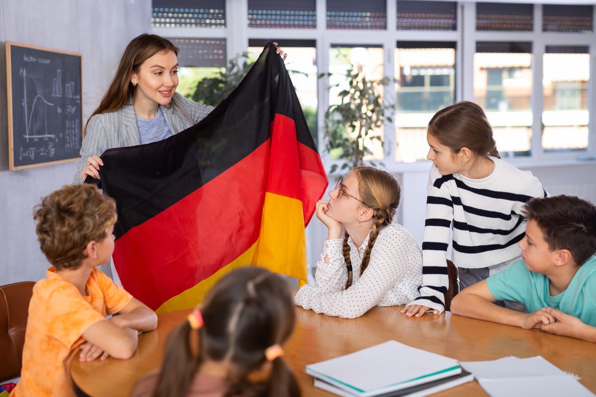 Preteens,Pupils,Looking,At,National,Flag,Of,Germany,While,Learning