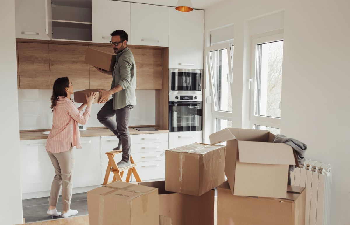Young,Couple,Storing,Carton,Boxes,In,Kitchen,High,Elements,,Moving
