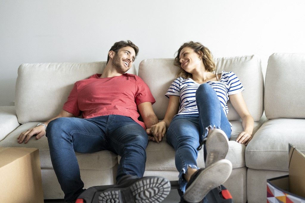 Young couple relaxing on sofa in their new house lakás otthon start