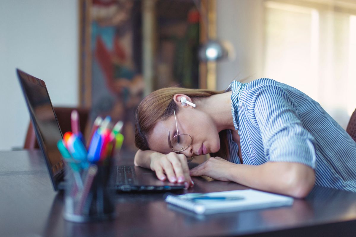 Young tired businesswoman sleeping on desk in home office munkaszüneti nap