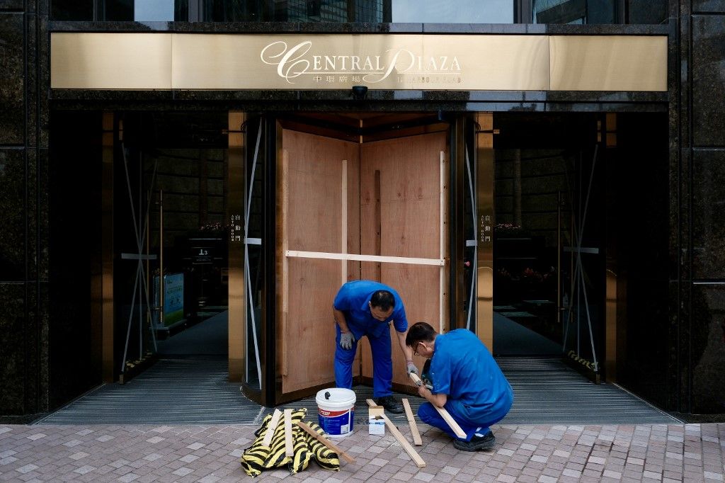 Workers install wooden boards at the entrance of a building in Hong Kong's Wanchai district, in preparation for Super Typhoon Ragasa on September 23, 2025. Hong Kong shut schools and cancelled flights on September 23 as Super Typhoon Ragasa was set to sla