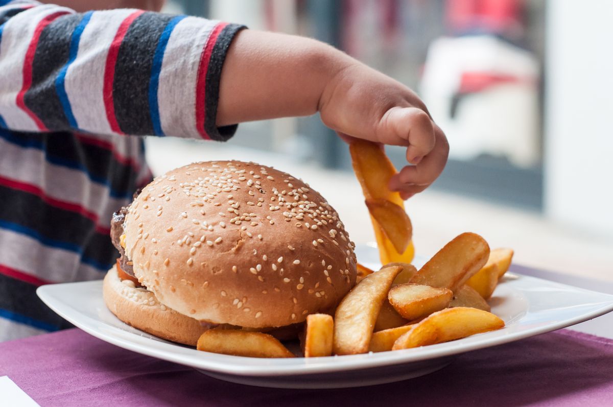 gyermek Closeup,Of,Little,Boy,Hand,Eating,Hamburger,And,French,Fries