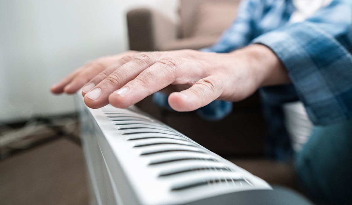 Man,Warms,Hands,Over,Electric,Heater,,Ideal,For,Small,Spaces