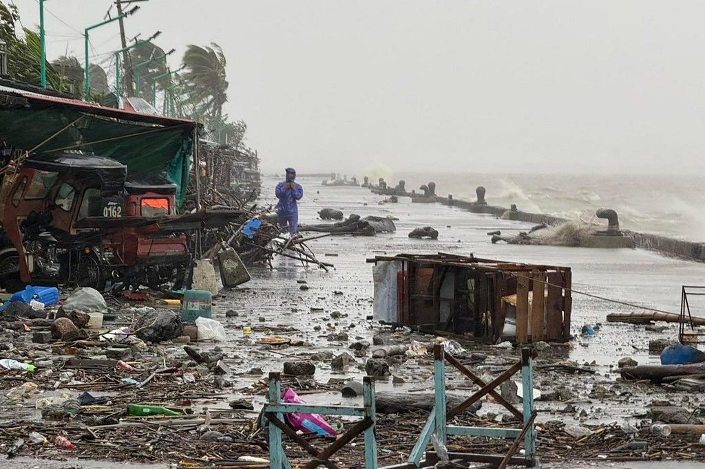 A man stands near debris on a waterfront road amid heavy rain due to weather patterns from Super Typhoon Ragasa in Aparri town, Cagayan province on September 22, 2025. Hundreds of families sheltered in schools and evacuation centres on September 22 as hea
