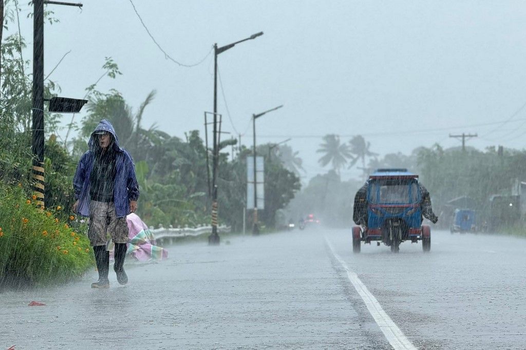 A man walks along a road amid heavy rain due to weather patterns from Super Typhoon Ragasa in Lal-lo town, Cagayan province on September 22, 2025. Hundreds of families sheltered in schools and evacuation centres on September 22 as heavy rains and gale-for