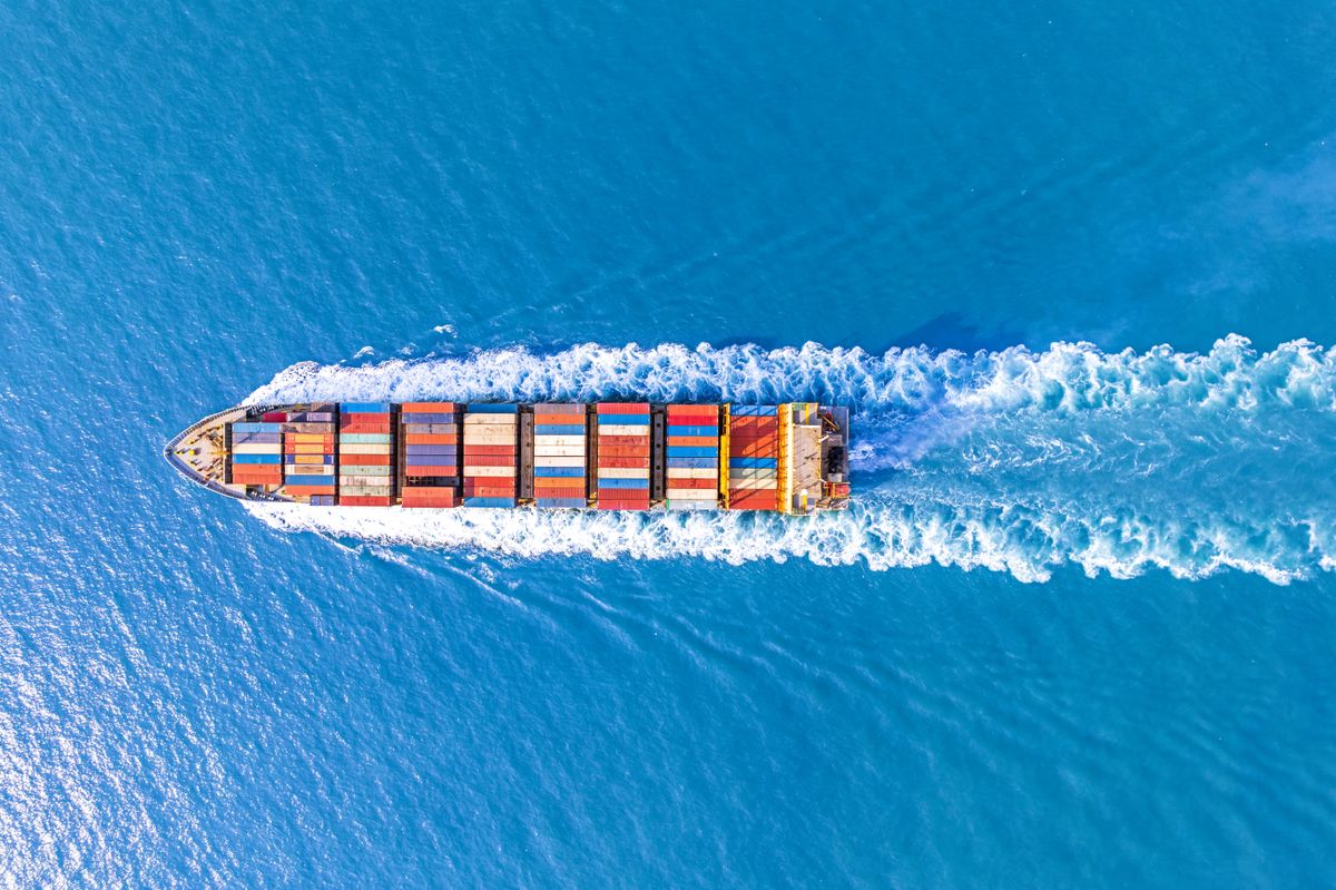 Aerial,Top,View,Of,Cargo,Ship,With,Contrail,In,The