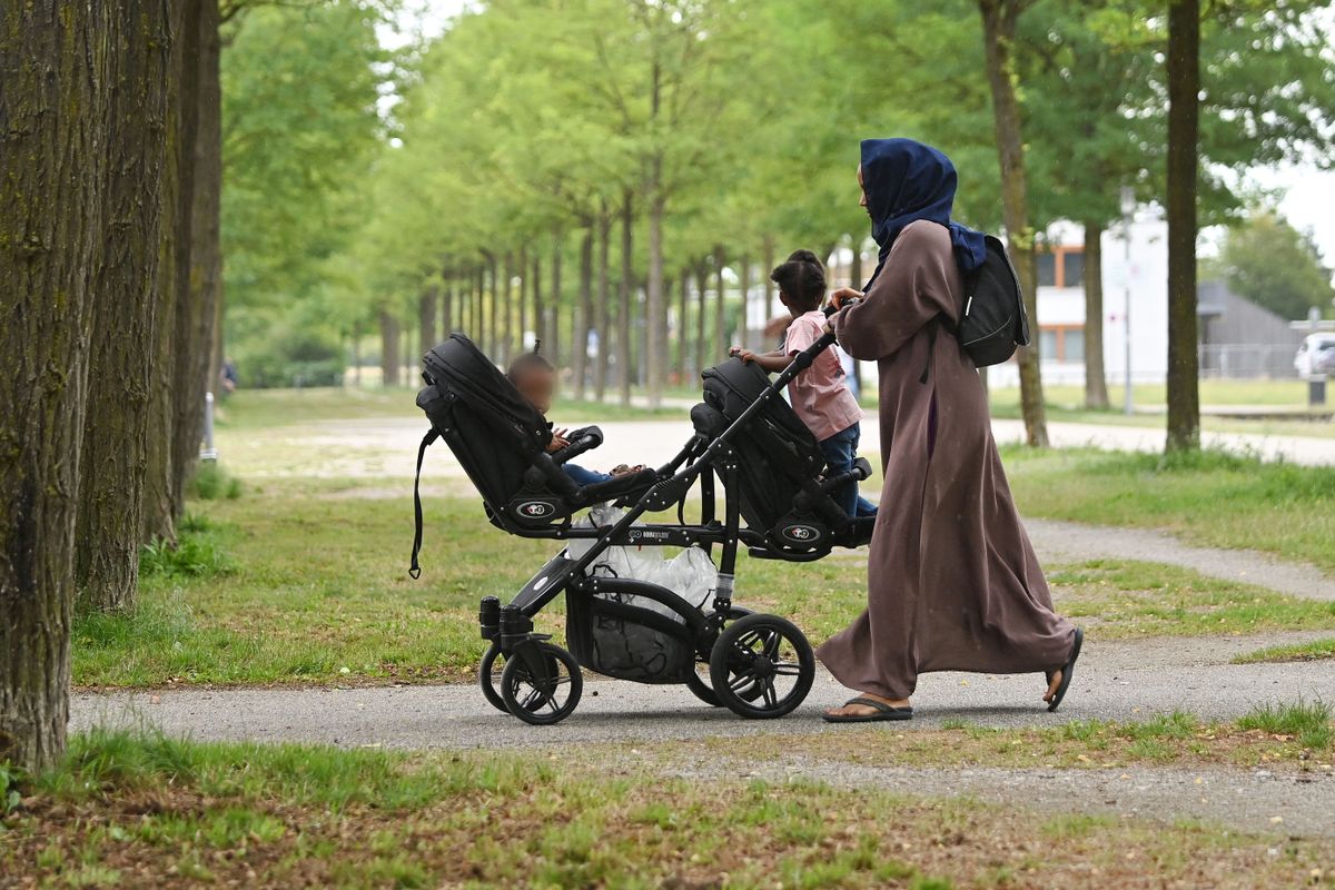 Muslim woman with headscarf, mother in traditional dress and headscarf with her children.