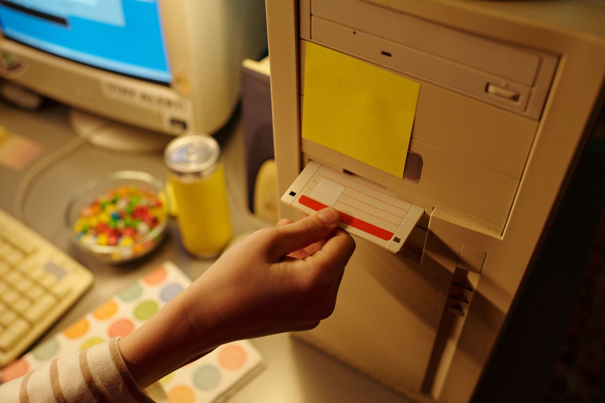 Hand,Inserting,Floppy,Disk,Into,Old,Desktop,Computer,Tower,With