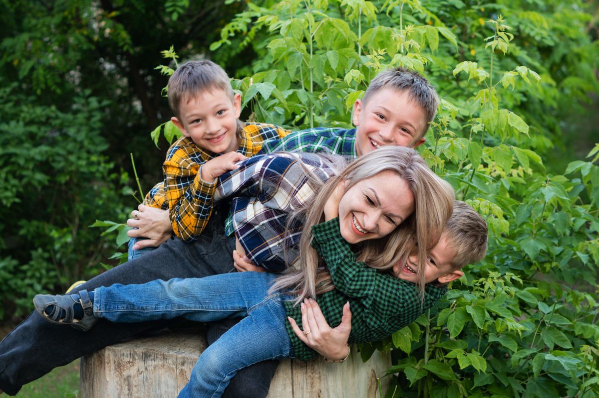Single,Parent,Family,With,Three,Children,Sitting,On,Tree,Stumpand