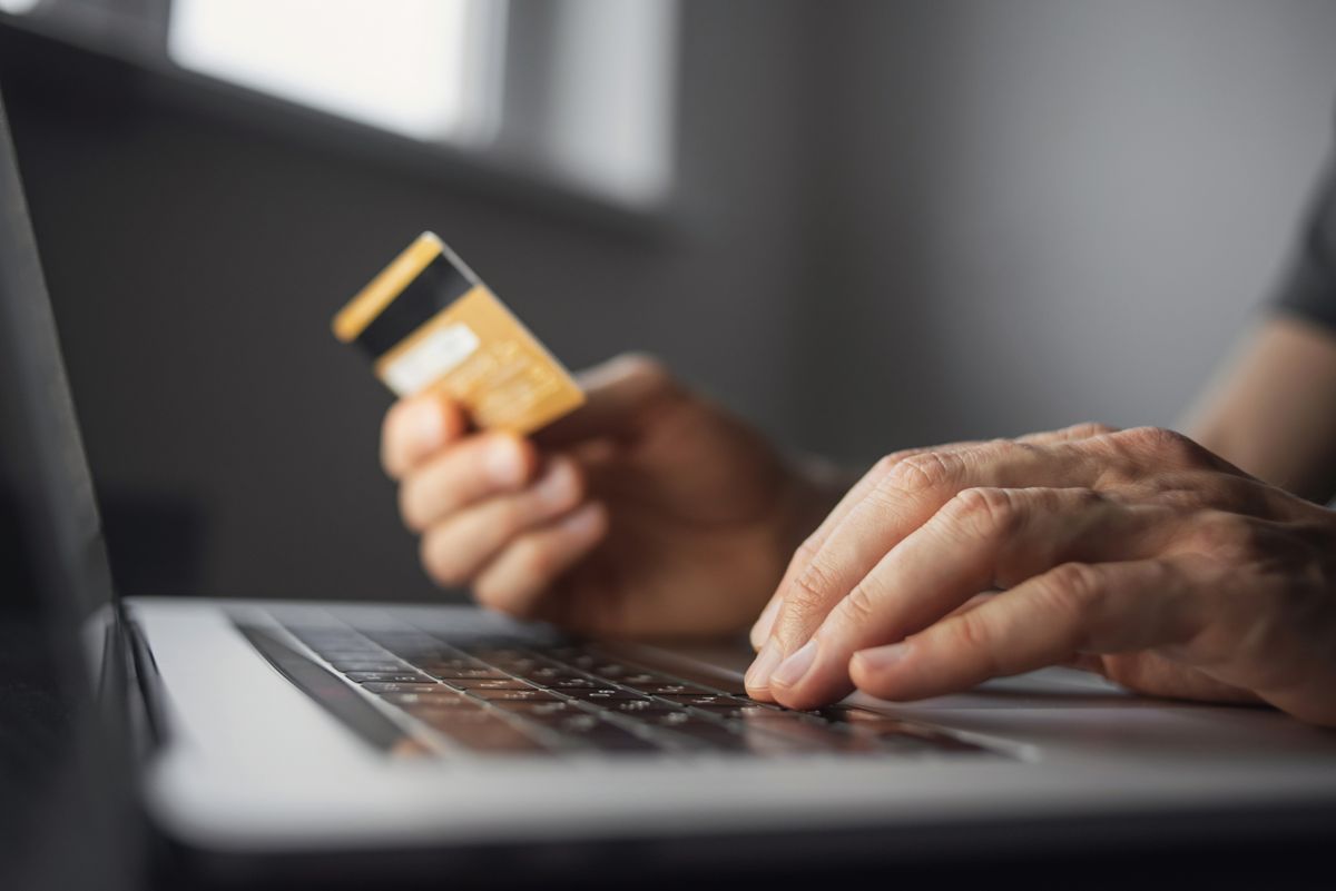 Végük van a csaló webárúházaknak Man,Hand,Holding,Credit,Card,And,Using,Laptop,At,Home.