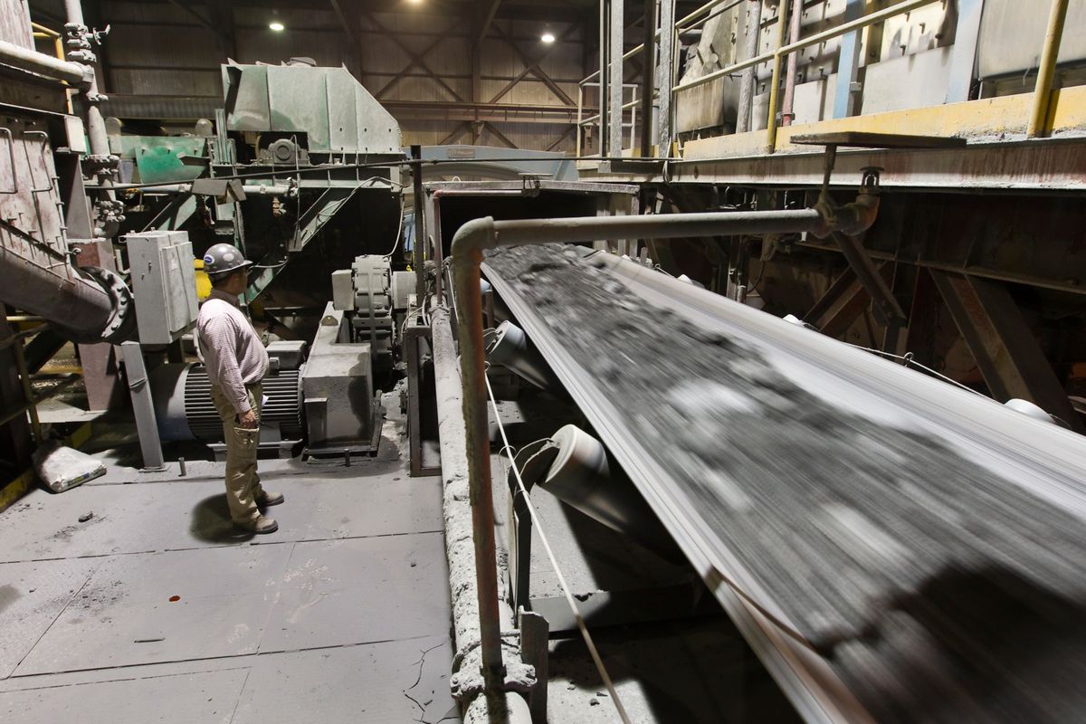 Worker stands next to a conveyer belt carrying gold ore in Kumtor mine extraction factory in Tien Shan mountains