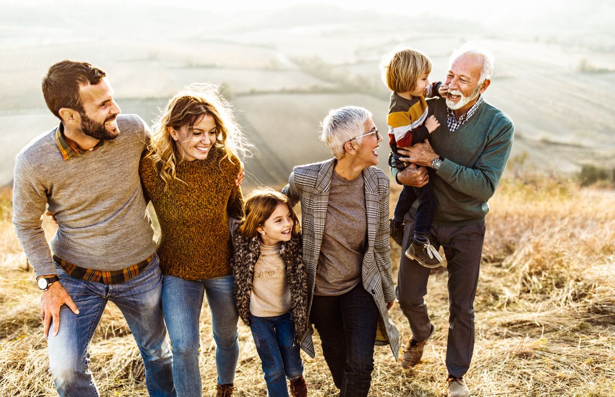 Happy multi-generation family talking while taking a walk on the field.
