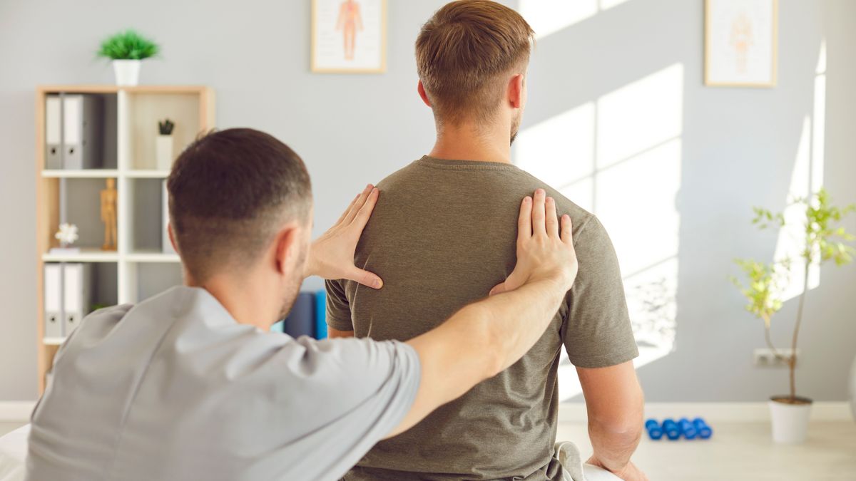 Male,Osteopath,Examining,Young,Man,In,Modern,Office.,Young,Physiotherapist