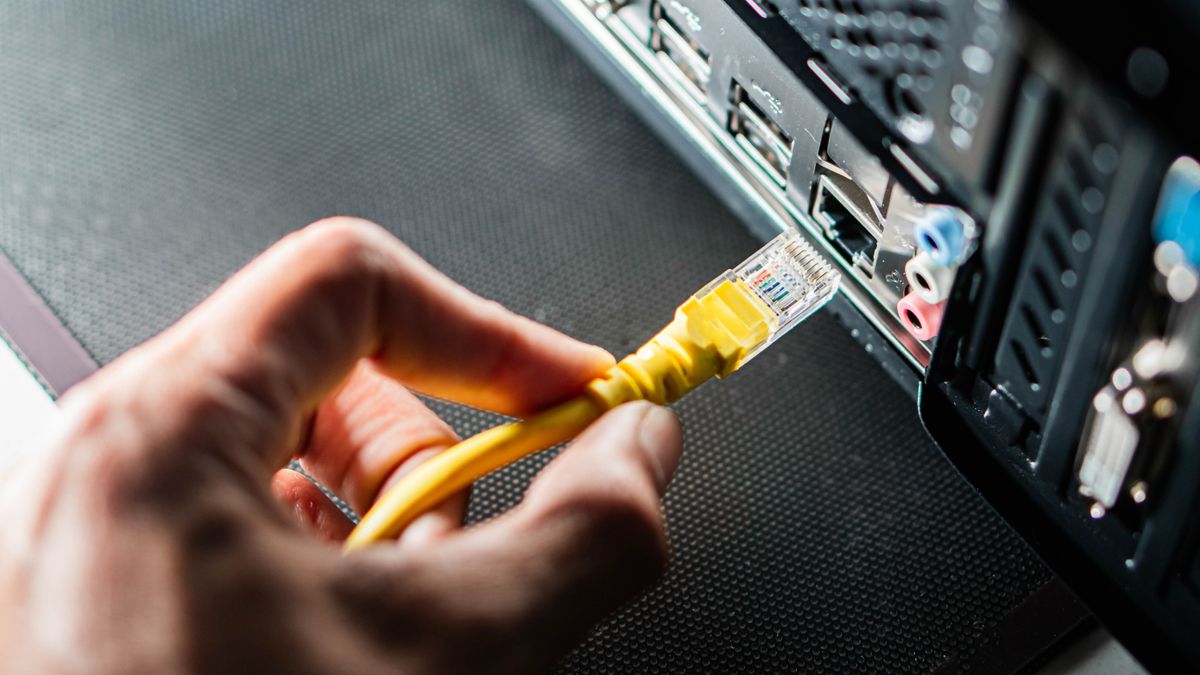 vidéki,A,Person,Plugging,A,Yellow,Ethernet,Cable,Into,The,Back