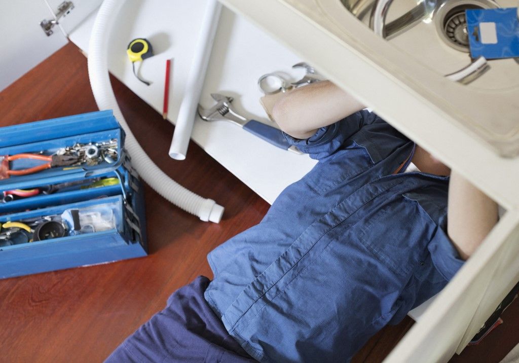 Plumber working on pipes under sink dugulás elhárítás csalás átverés