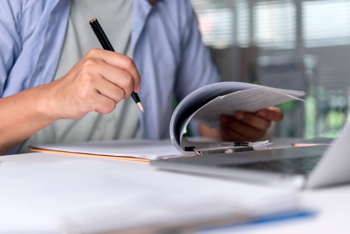 Office,Worker,Reviews,Document,,Paperwork,With,Pen,,Writing,Notes,Beside