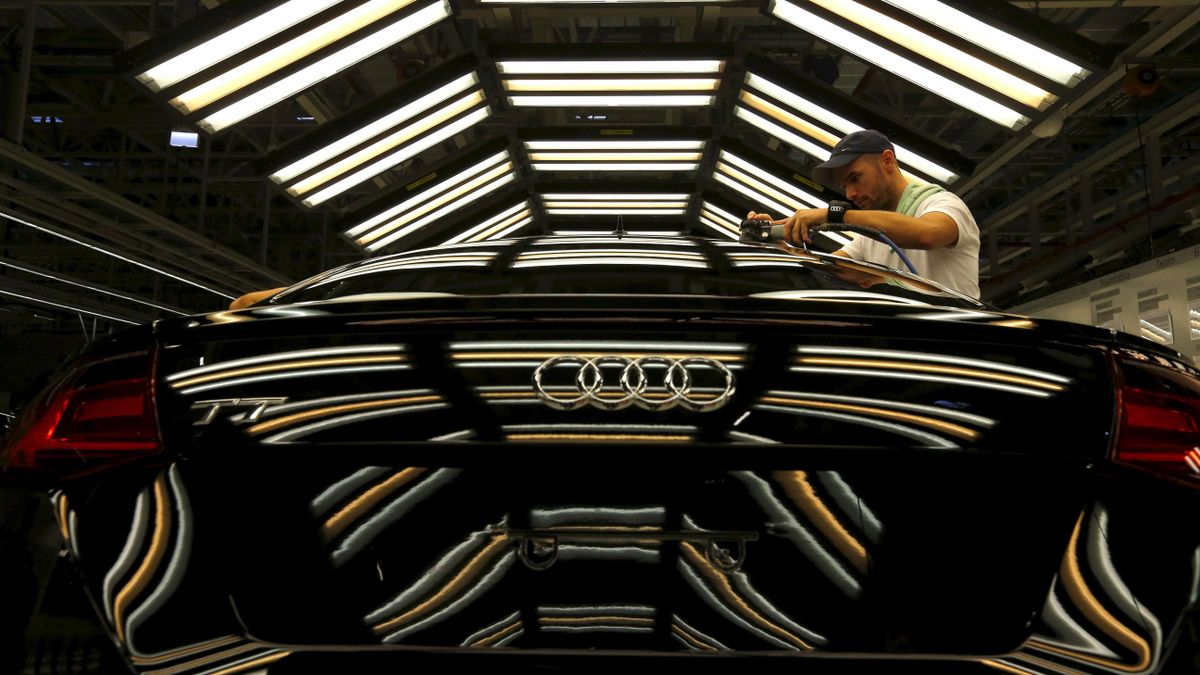 A worker stands next to a car on the assembly line as serial production of the new Audi TT roadster starts at the Audi plant in Gyor, west of Budapest