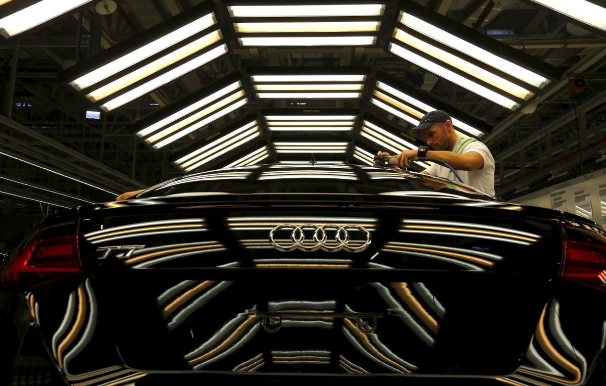 A worker stands next to a car on the assembly line as serial production of the new Audi TT roadster starts at the Audi plant in Gyor, west of Budapest