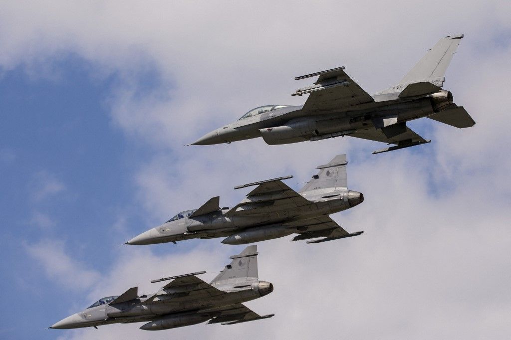 JAS-39 Gripen aircraft of the Czech Air Force fly in formation with a U.S. Air Force F-16 Saab