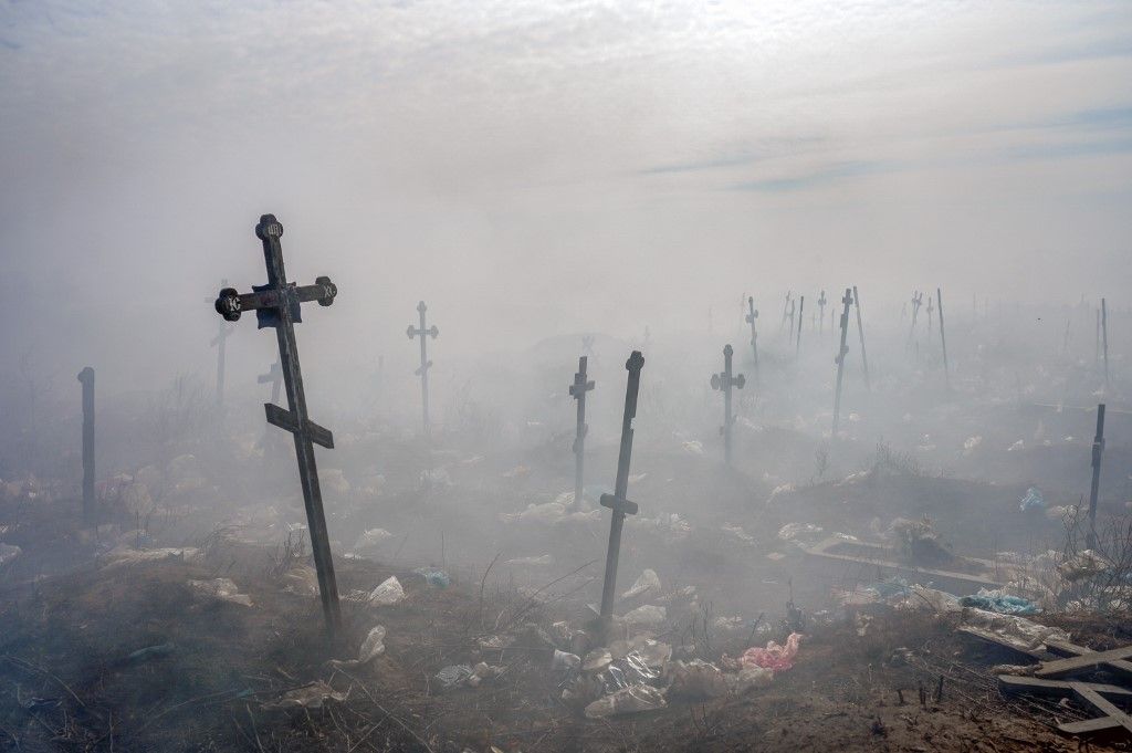 EDITORS NOTE: Graphic content / (FILES) Crosses are seen through smoke in the cemetery of Mykolaiv, southern Ukraine, on March 21, 2022. (Photo by BULENT KILIC / AFP)