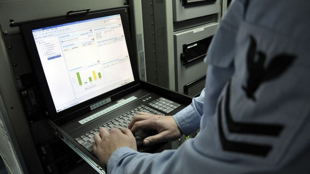 Information Systems Technician monitors network activity from a laptop, ügynökbotrány