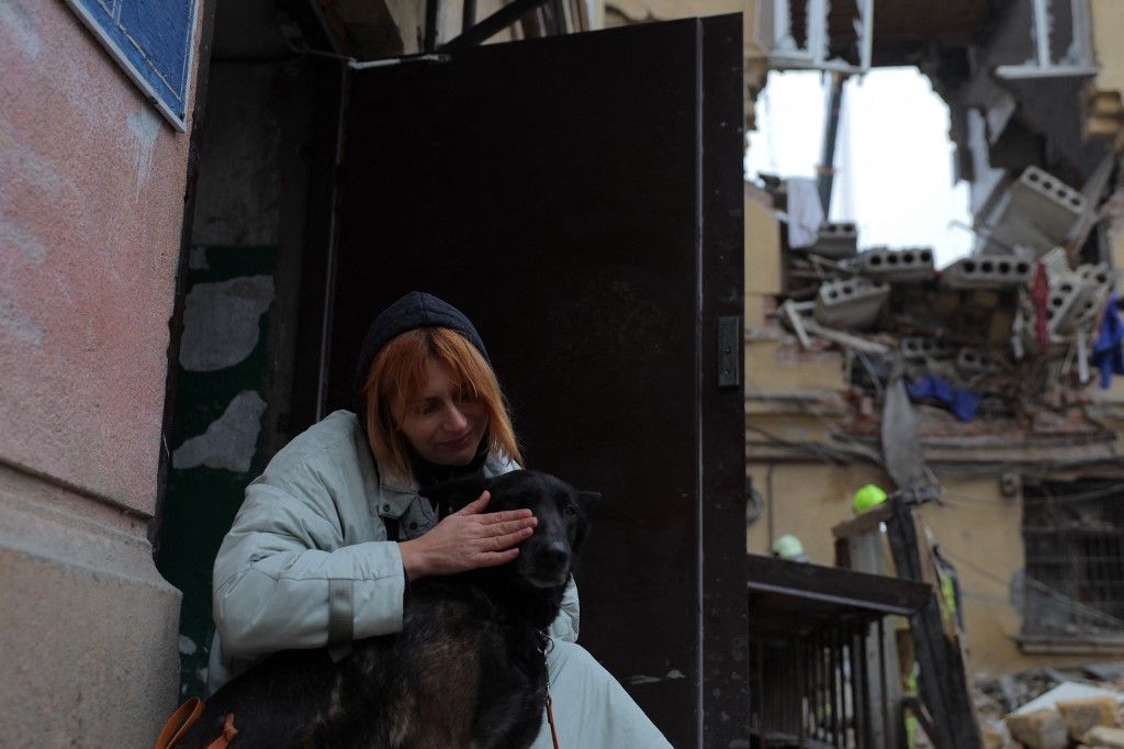 A local resident pets her dog at the site of a heavily damaged residential building following an air attack in Odesa on January 27, 2026, amid the Russian invasion of Ukraine. (Photo by Oleksandr GIMANOV / AFP)