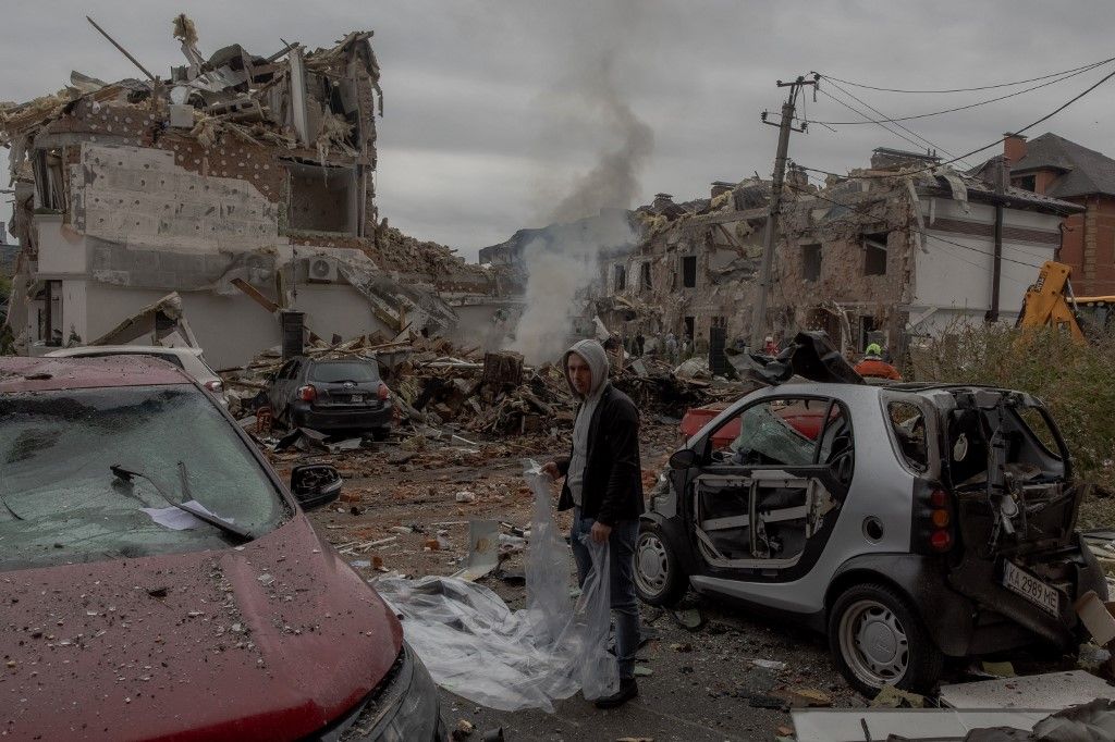 (FILES) A man prepares to cover a damaged car with a plastic sheet at the site of heavily damaged residential buildings following a Russian air attack on the outskirts of Kyiv, on September 28, 2025, amid the Russian invasion of Ukraine. An overnight Russ