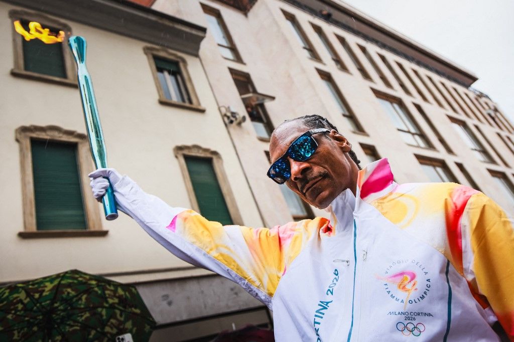 This handout picture taken and released on February 04, 2026 by the Milano Cortina 2026 Olympic Committee shows US rapper Snoop Dogg carrying the torch of the Olympic flame in Gallarate, ahead of Milano Cortina 2026 Olympic Games. (Photo by Handout / Mila
