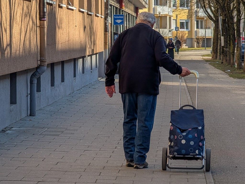 At-risk-of-poverty. Retiree With A Shopping Trolley In A Munich Residential Area nyugdíj