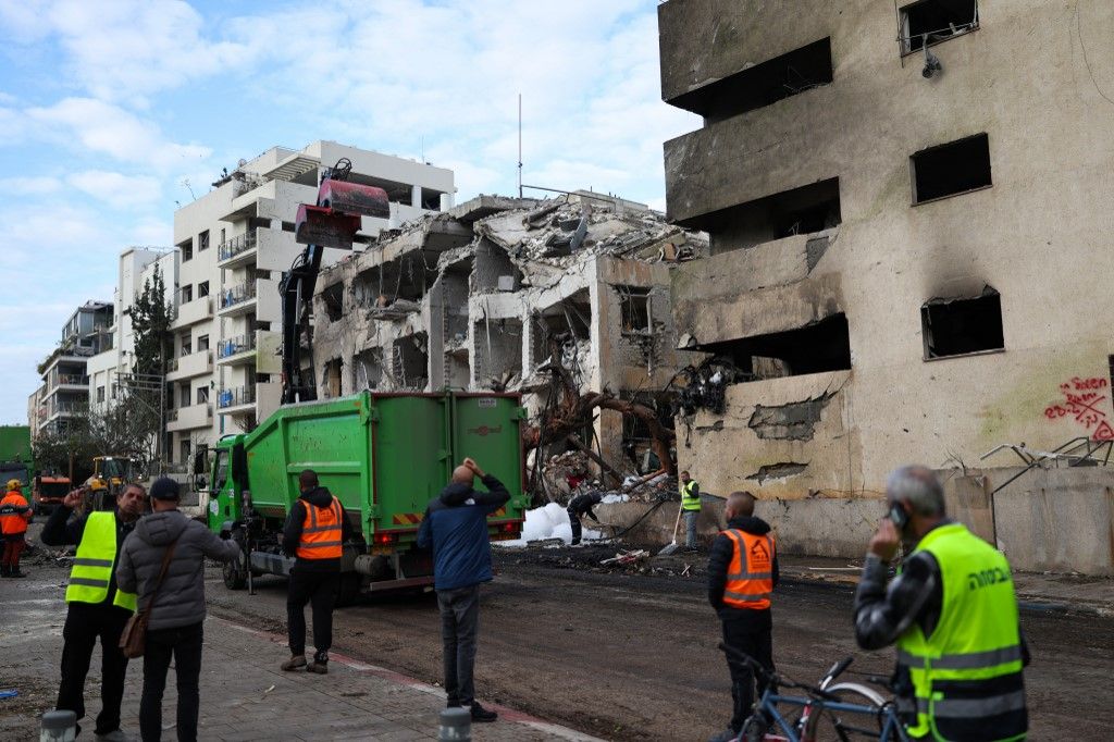 People look at a building damaged in a reported overnight Iranian strike in Tel Aviv on March 1, 2026. US President Donald Trump said February 28 that Iran's supreme leader Ayatollah Ali Khamenei was dead, after Israel and the United States launched an at