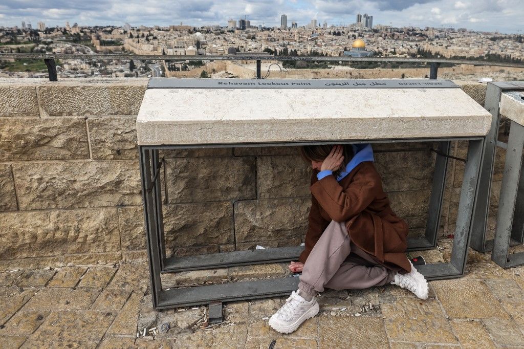 A person takes shelter as sirens sounded in Jerusalem on February 28, 2026, following the announcement that Israel had launched a “preemptive strike” on Iran. Israeli Prime Minister Benjamin Netanyahu said Iran must not be allowed to gain nuclear arms and